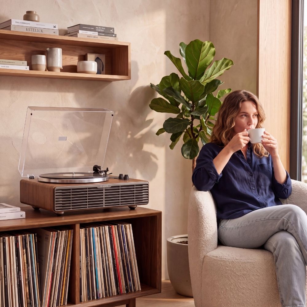 Écoute d'un disque sur la platine vinyle Volute Noyer dans un salon, devant une collection de vinyles